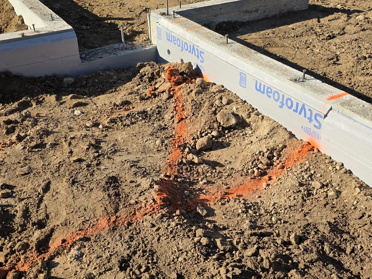 Foam-faced stem walls and marked under-slab plumbing lines at the Eagle custom home addition, week of September 28, 2026.
